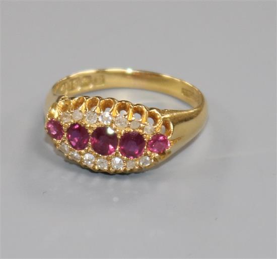 An early 20th century 18ct gold, five stone ruby elliptical shaped ring with diamond set border, size O.